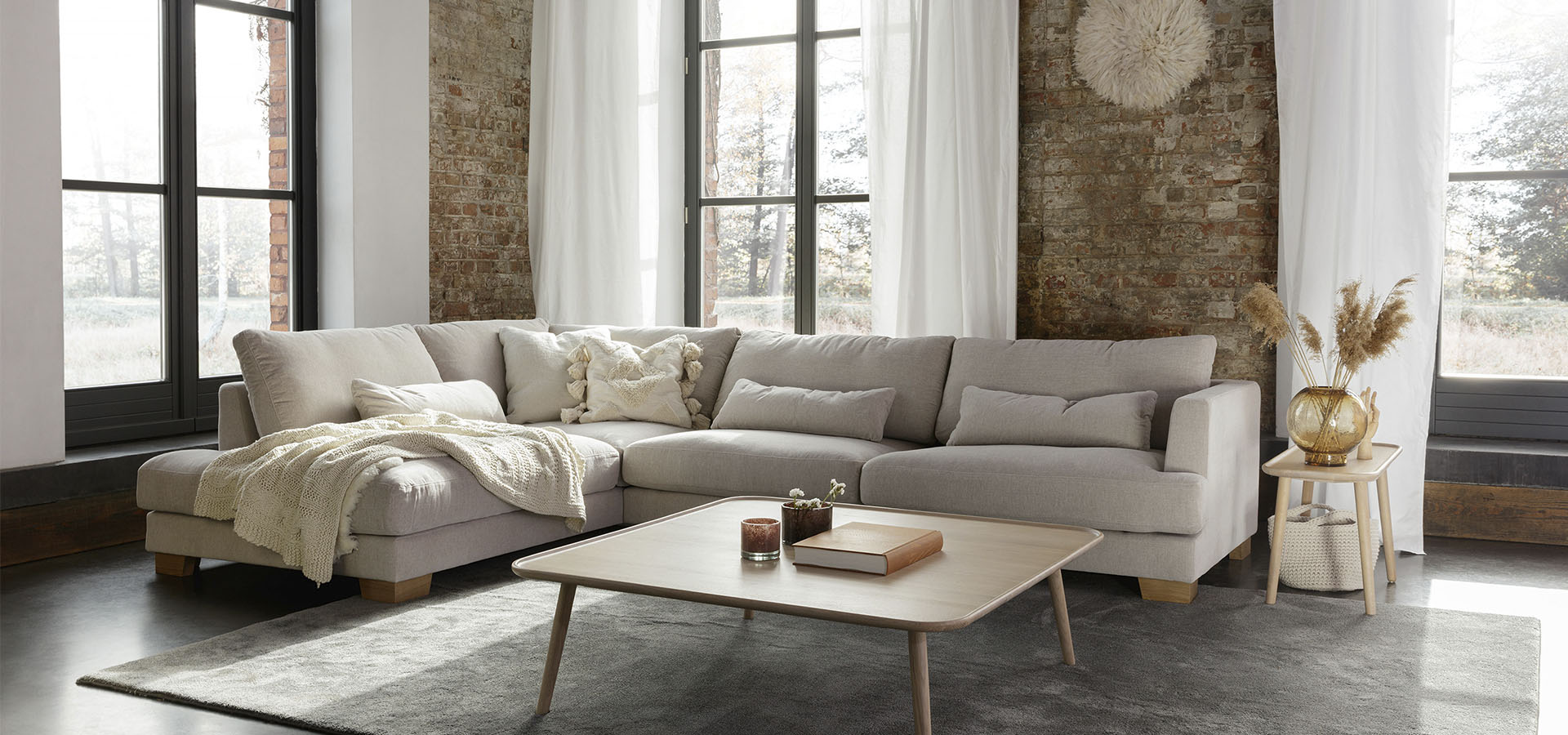 Sitsin beige Brandon-divaanisohva tiilisein&auml;n ja ikkunoiden edess&auml;