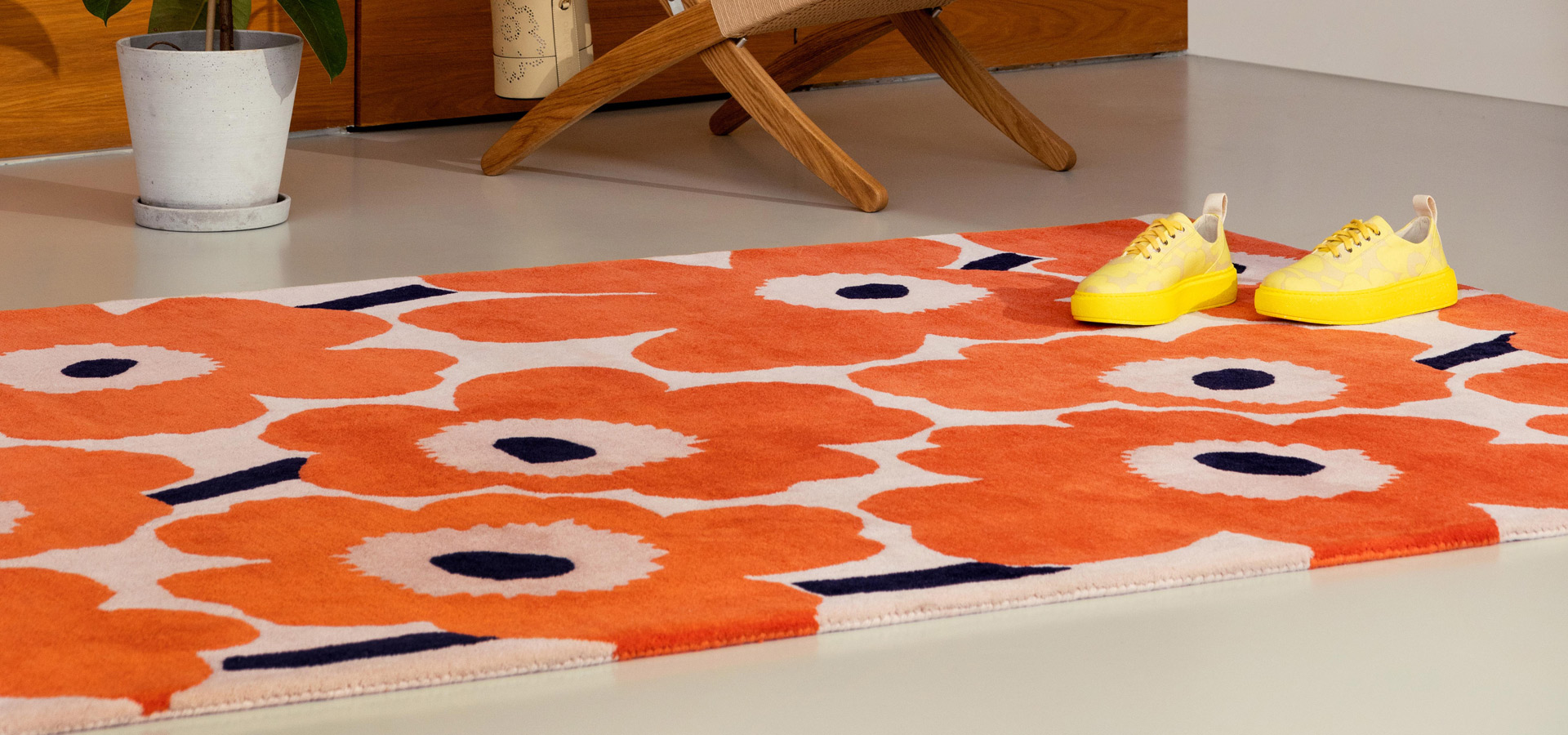 Oranssi kukkakuosinen villamatto, jonka p&auml;&auml;ll&auml; kirkkaankeltaiset keng&auml;t.