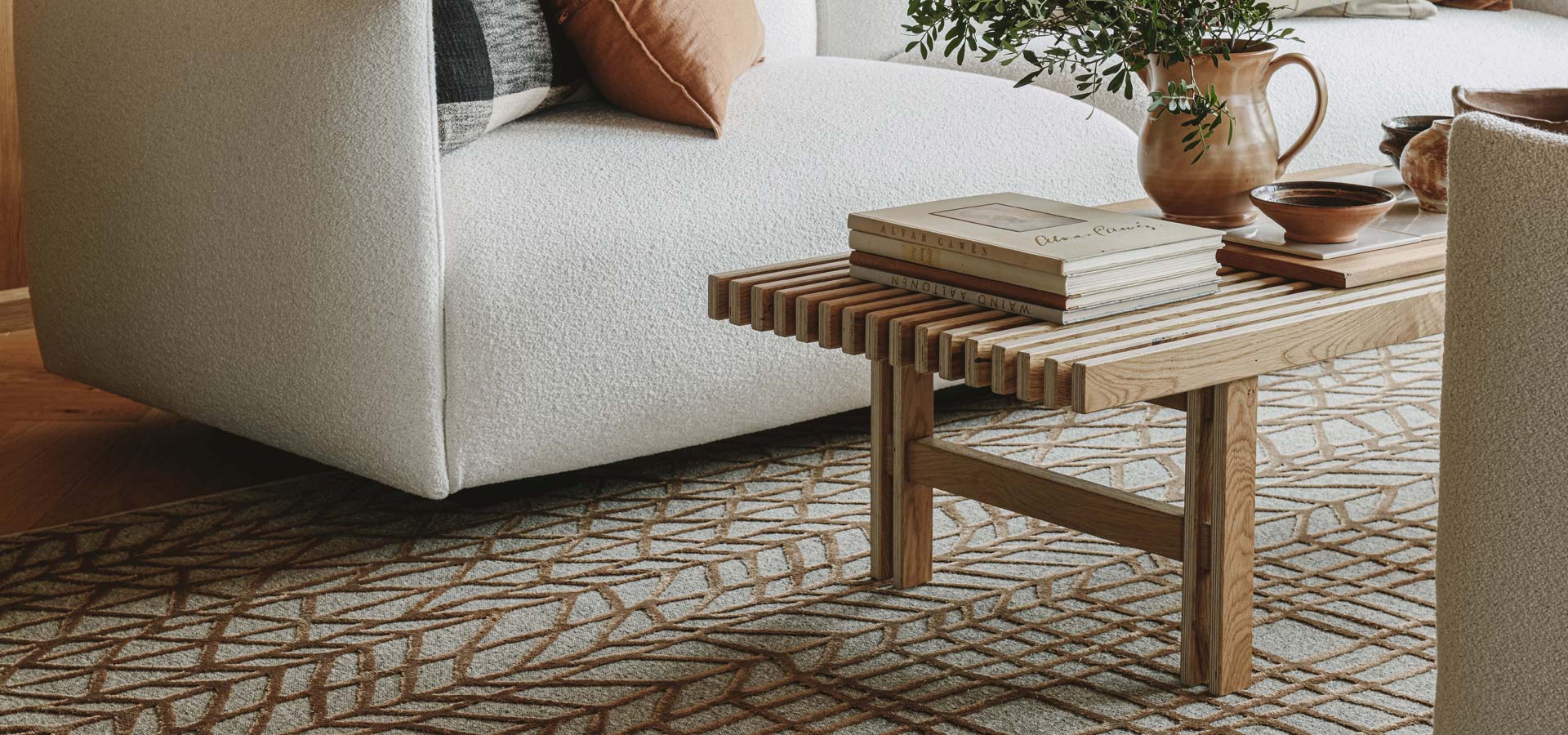 Olohuhuoneen lattialla on matto, jossa on graafinen, kuparinv&auml;rinen kuviointi.